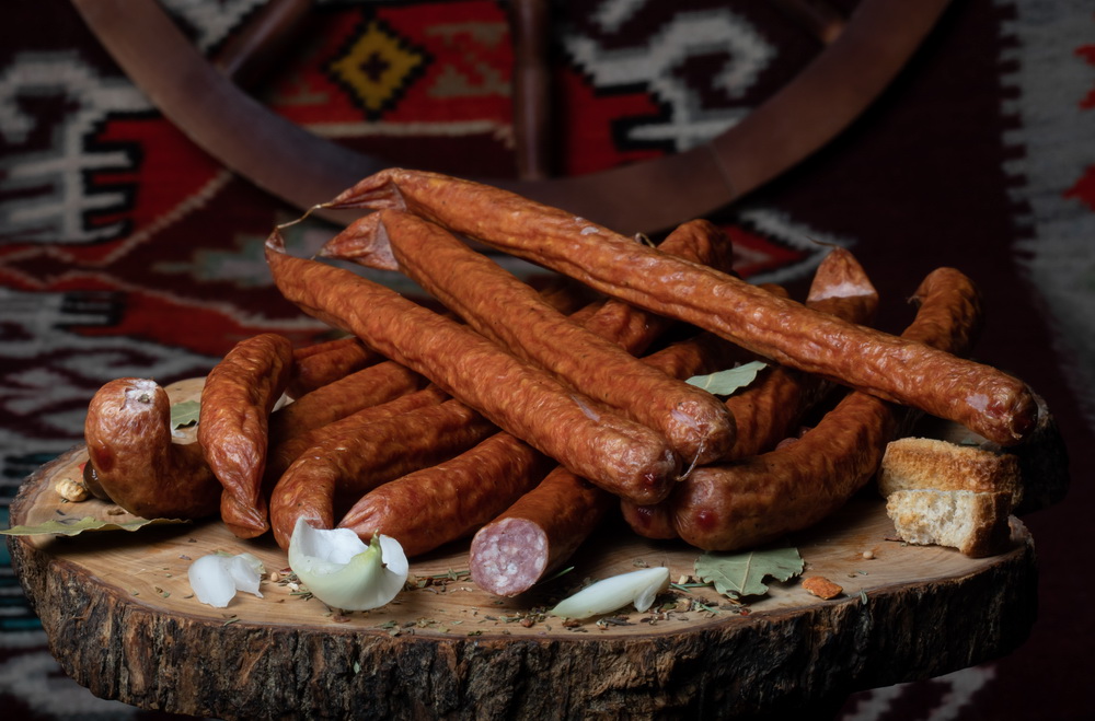 CABANOS ŢĂRĂNESC: Produs fiert și dublu afumat cu membrană naturală comestibilă din carne porc și vită, aromatizat cu condimente naturale.